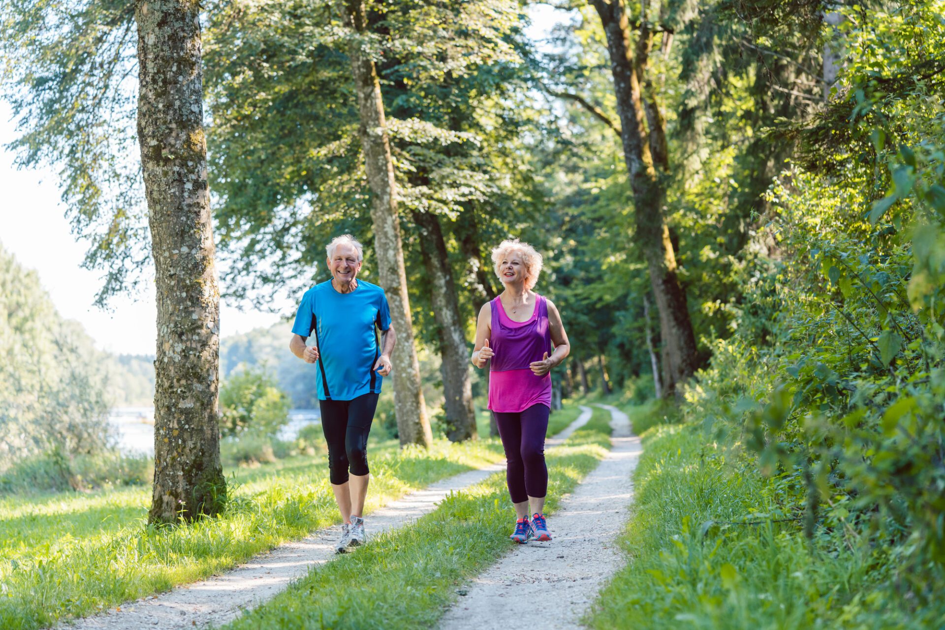 Two active seniors with a healthy lifestyle smiling while joggin