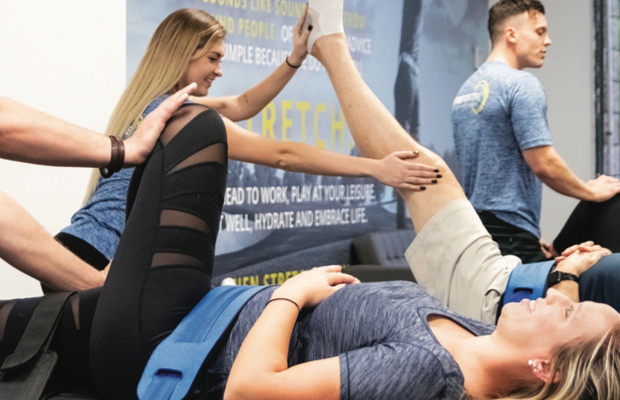 Multiple stretch practitioners performing stretches on clients at a Stretch Zone studio